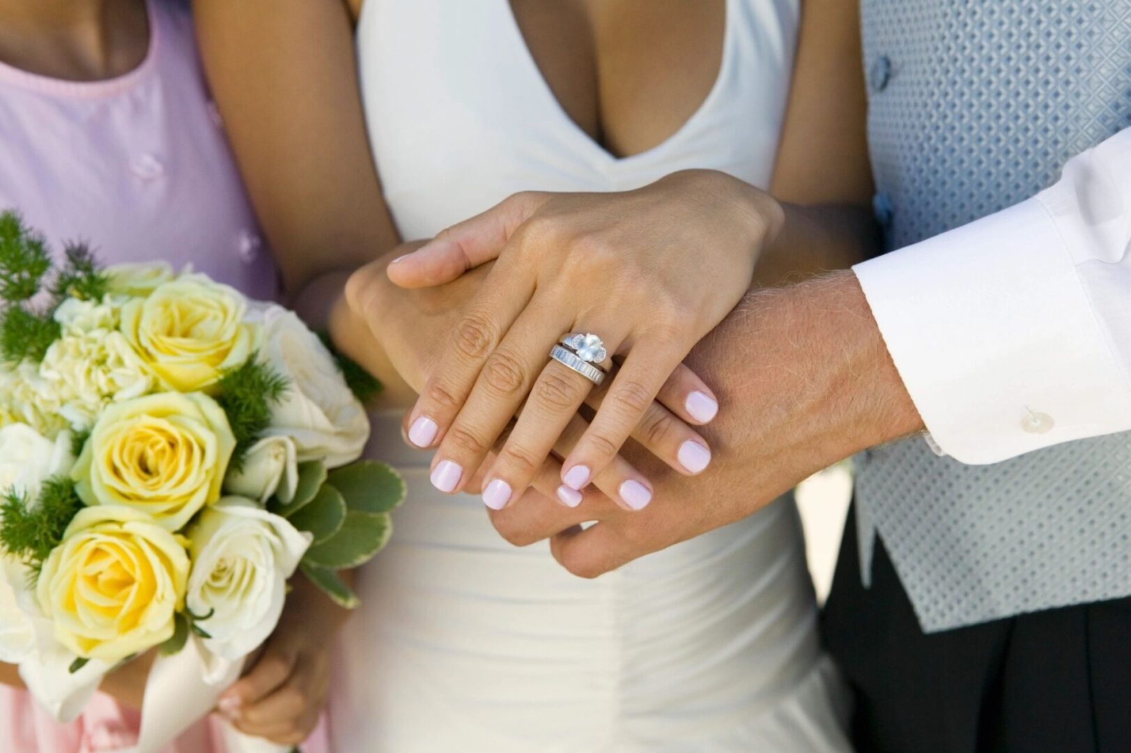 A bride and groom holding hands with their wedding rings.