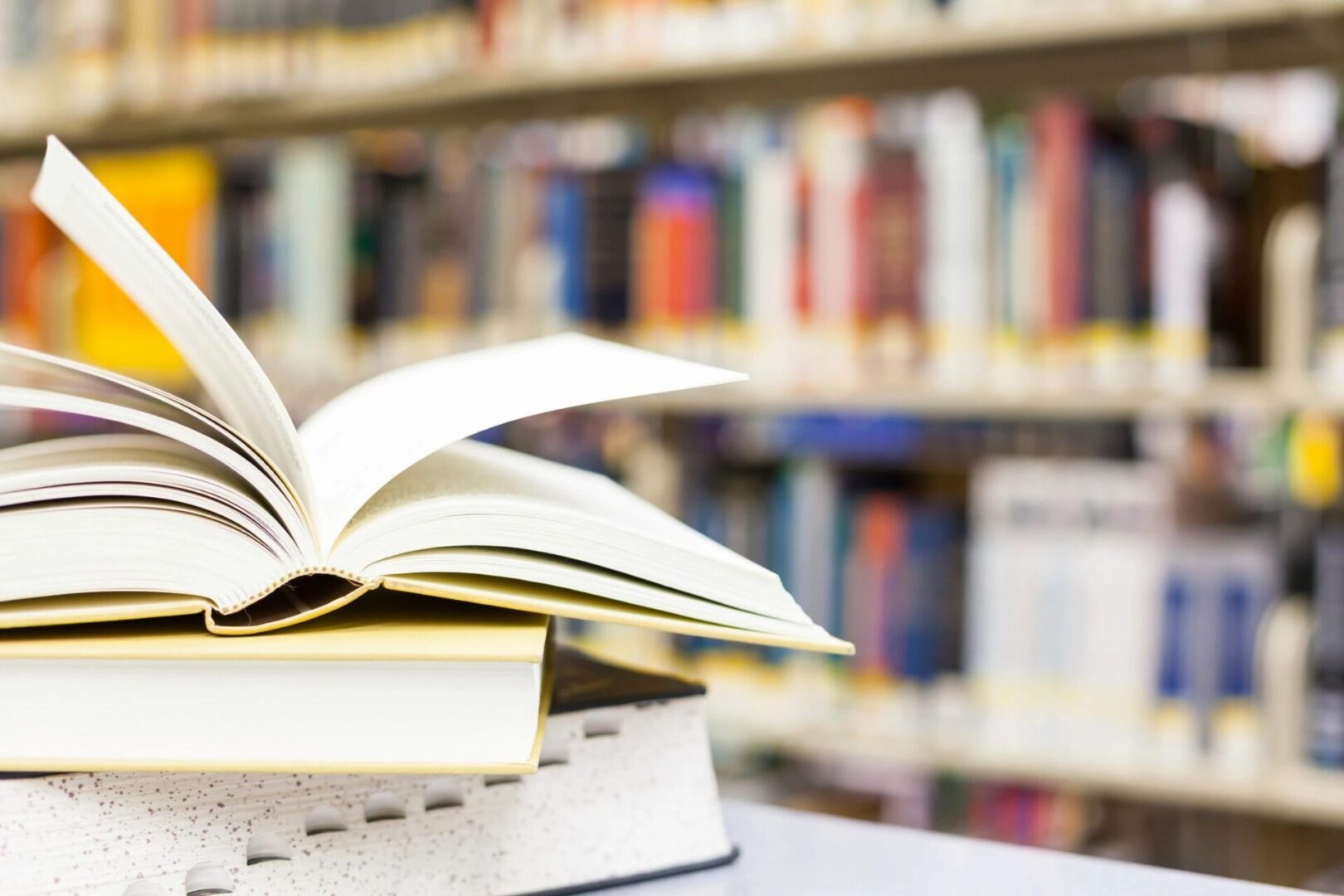 A book is open on the table in front of some books.