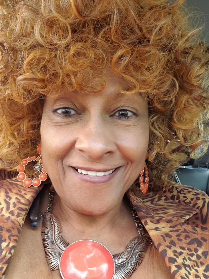 A woman with curly hair and orange earrings.