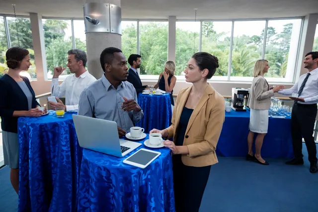 Two people standing at a table with laptops and coffee.