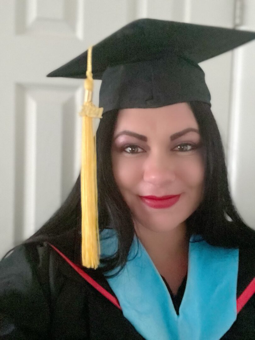 A woman in graduation gown and cap with yellow candle.