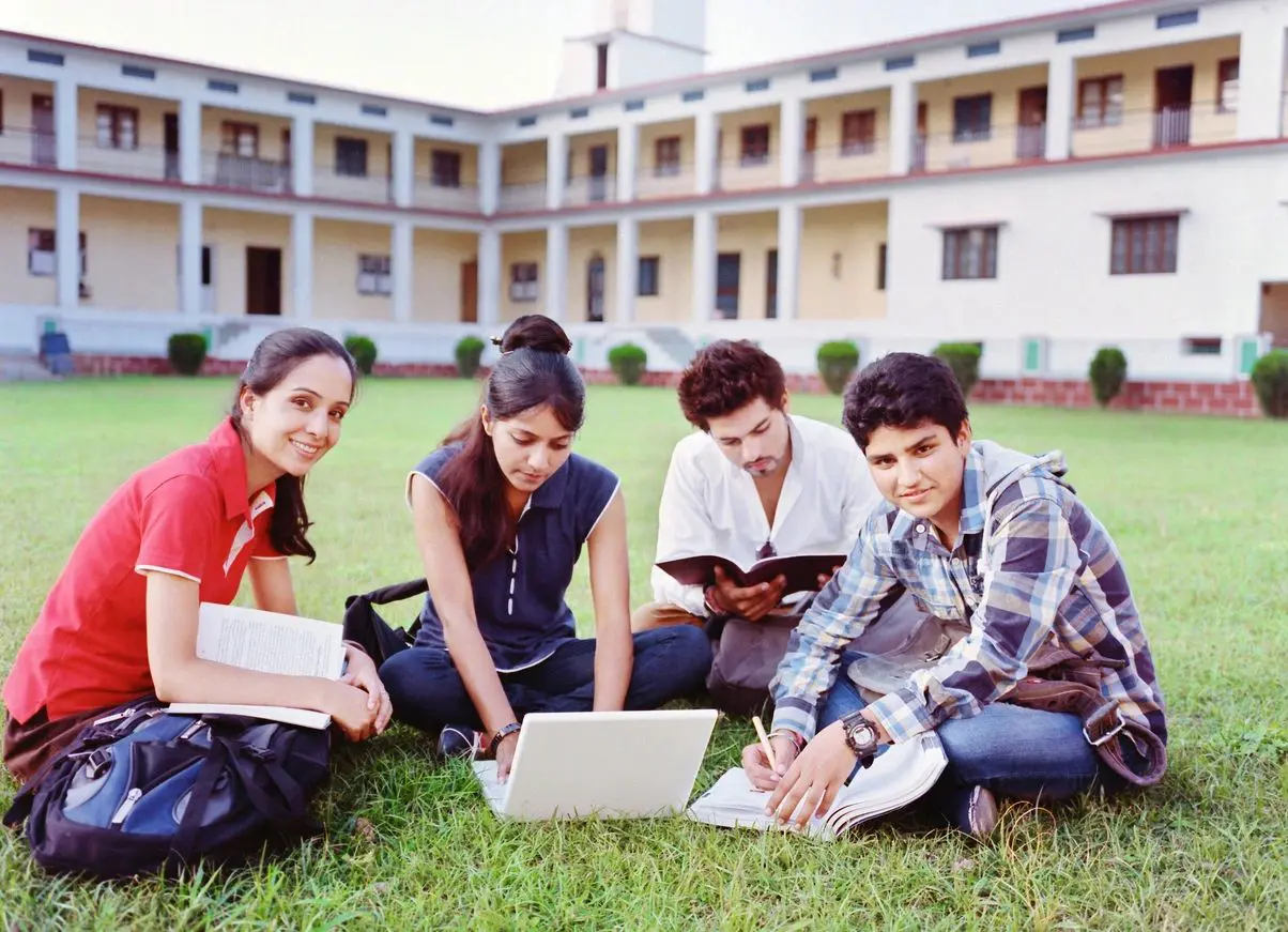 A group of people sitting on the grass with laptops