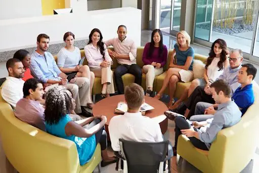 A group of people sitting around each other in a circle.