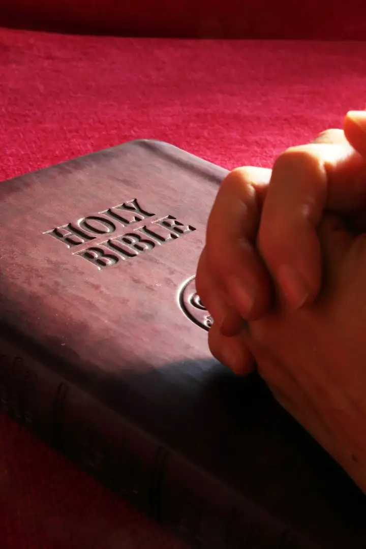 A person is holding their hands over the bible.