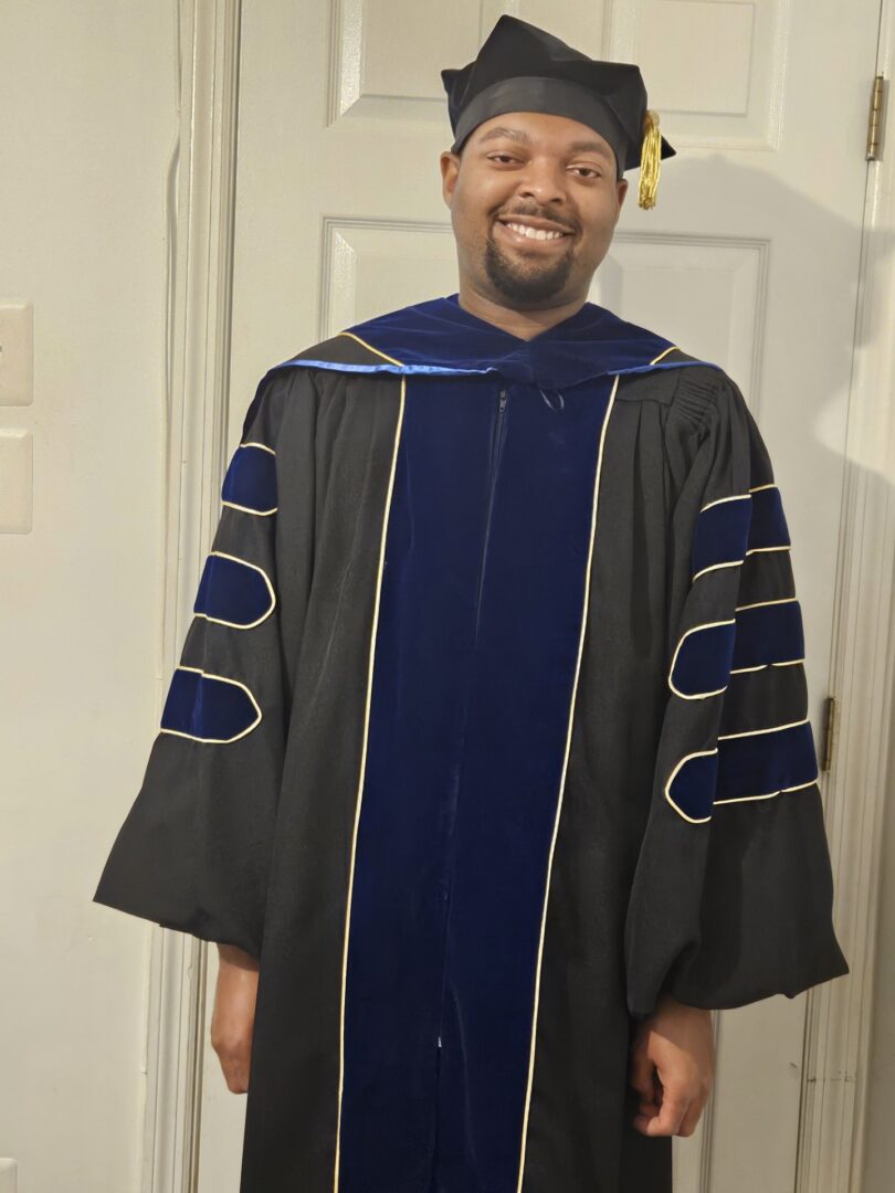 Man in graduation gown and cap smiling.